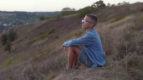 A boy walking alone in the hills at sunset Stockbeeldmateriaal 140181841