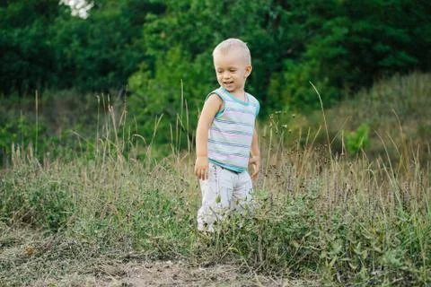 A boy is walking along a clearing in the grass Stock Photos