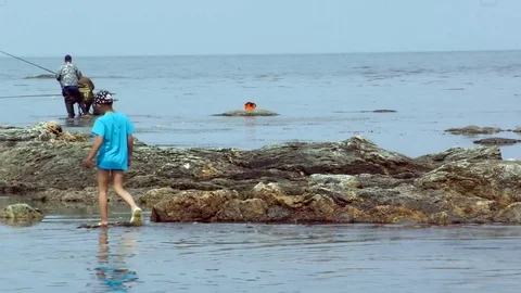 The boy is walking along the reefs Stock Footage 77457140