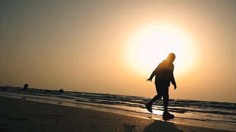 A boy is walking along the sea side looking for something Stock Footage 99606796