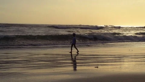 Boy walking on the beach next to the sea, steadycam shot, slow motion shot at 24 Stock Footage 79382950