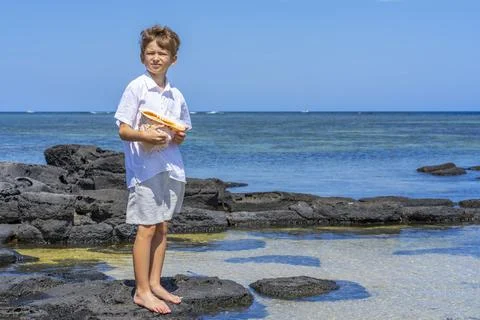 A boy walking with a big seashell in his hand on the tropical beach. Foto stock