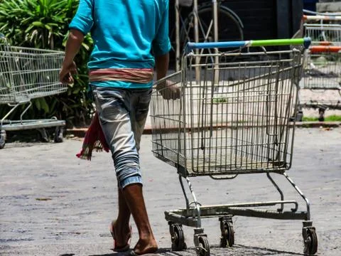 Boy walking with empty trolley outside of super market. Foto stock