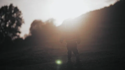 Boy walking on the hill at sunset with silhouette Stock Footage 254003953