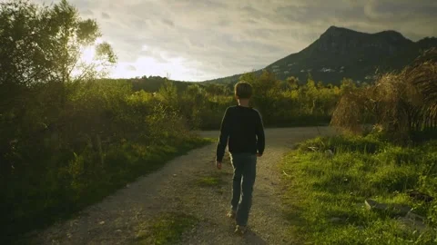A boy walking in a mountain valley at dawn. Back view. Montenegro. Stock Footage 321750276