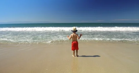 Boy walking on the ocean sand Stock Footage 102689980