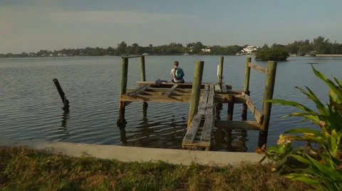 Boy walking on an old dock toward water Video stock 64107481