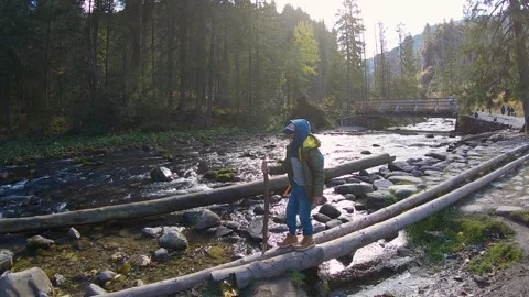 Boy walking over the river stones in front of trees  in Zakopane, Poland Stock Footage 152845294
