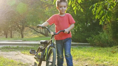 Boy walking in the park with a bicycle Stock Footage 141354836