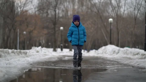 Boy walking in a puddle at winter. Stock Footage 151527122