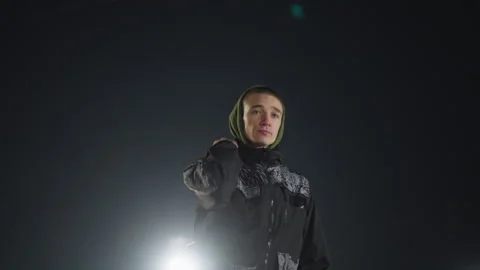 Boy walking with skate boot over shoulder under night sky with arena lights Stock Footage 316452960