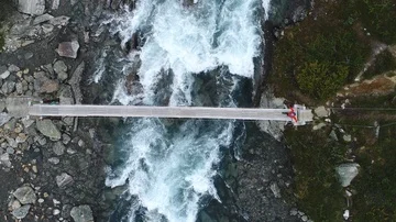 Boy walking through a rope bridge over the river in mountains. Stock Footage 85715288
