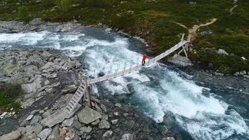 Boy walking through a rope bridge over the river in Norweigan mountains. Stock Footage 85844579