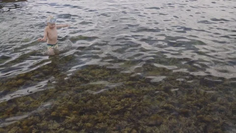 The boy walks on algae growing at the bottom of the sea. Slowmotion Stock Footage 94224625