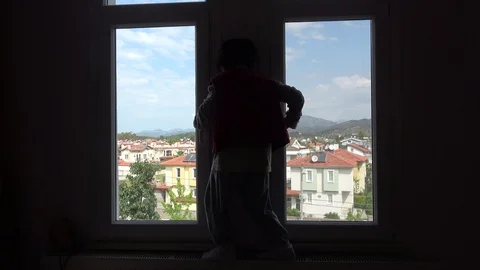 Boy walks along radiator below the window and beats his fist against the gla Stock Footage 128187773
