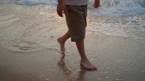 A boy walks barefoot along the sandy beach Stock Footage 312831860