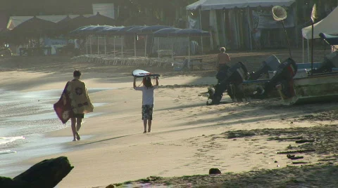 A boy walks down the beach with a surfboard on his head Stock Footage 574293