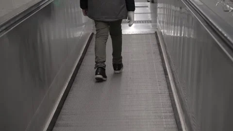 The boy walks down the escalator in the subway. Close-up of legs Video stock 251159092