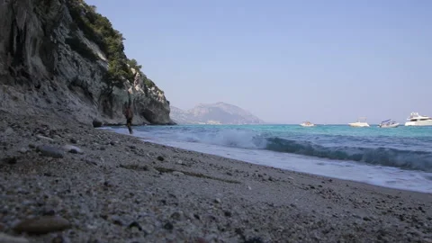Boy walks on the shore, blue rough sea Stock Footage 139524815