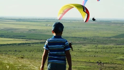 The boy walks the steppe over which paragliders soar Stock-Footage 76761418