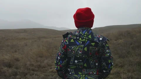 Boy walks through valley with dry grass during first snow Stock Footage 130378891