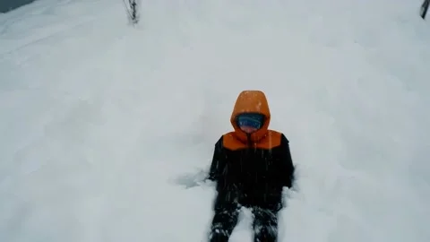 A boy in warm clothes falls on the snow and makes an angel in the snow. Stock Footage 169538086