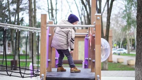 A boy in warm clothes plays on the playground, outdoors Stock Footage 171212671