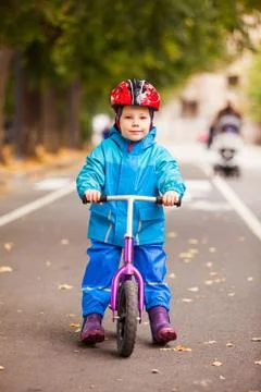 Boy in warm jacket siting on his balance bike Stock Photos