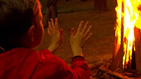 Boy warms his hands by the fire Stock Footage 115988401
