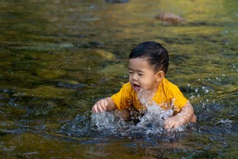 The boy was having fun playing in the water for the first time in the stream. Stock Photos