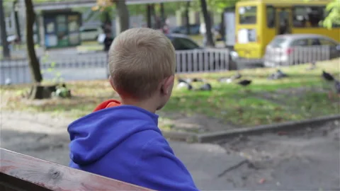 The boy was sitting on a bench in the spring Video stock 86970367