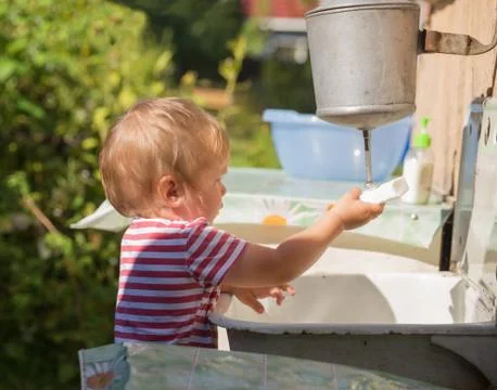 Boy washes his hands under washstand Stock Photos