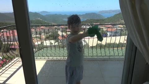Boy washes window at the balcony with beautiful sea view Stock Footage 201481235