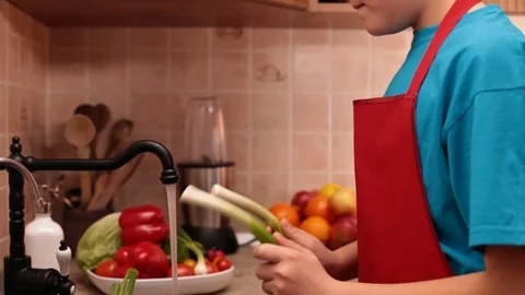 Boy washing vegetables at the kitchen sink Stock Footage 75418138