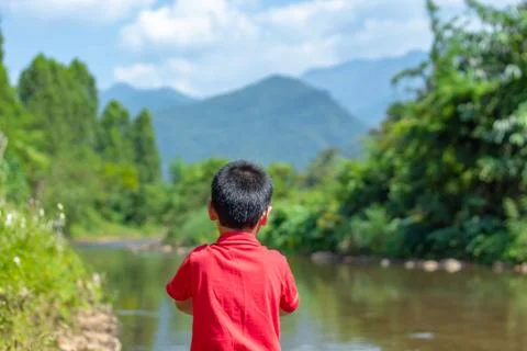 The boy watched the stream flow from the mountains, The background mountains  Stock Photos