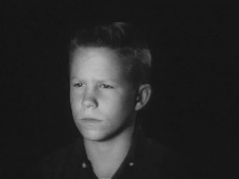 A boy watches an atomic bomb exploding into a mushroom cloud, on television, in Video stock 74972696