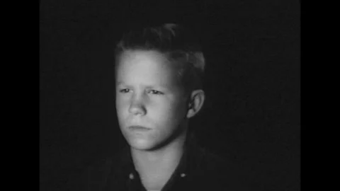 A boy watches an atomic bomb exploding into a mushroom cloud, on television, in Video stock 139705185