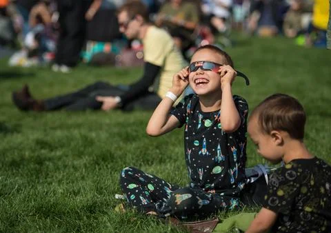 A boy watches the total solar eclipse through protective glasses in Madras,.. Stock Photos