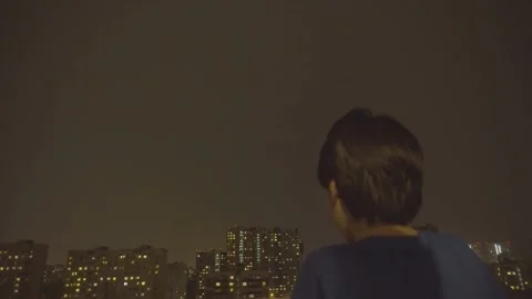 Boy Watching Lightning Storm Over Night City Sky Stock Footage 131387493