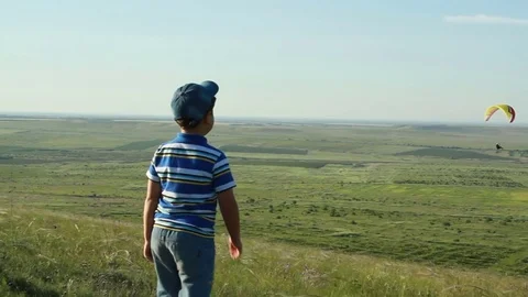 The boy is watching the paraglider 스톡 동영상 76737247