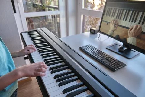 Boy watching piano tutorial video with computer. Stock Photos