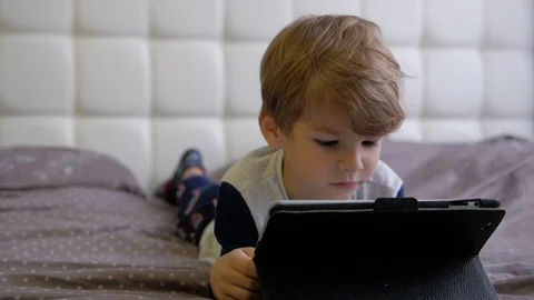 Boy watching tablet while lying on bed Stock Footage 98134653