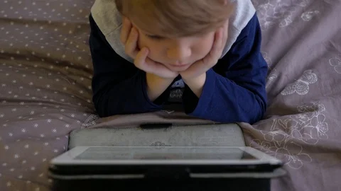 Boy watching tablet while lying on bed Stock Footage 98134675