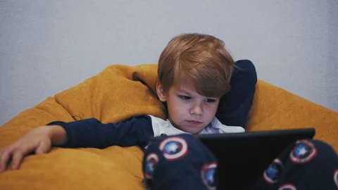 Boy watching tablet while sitting on a pouf Stock Footage 100124630