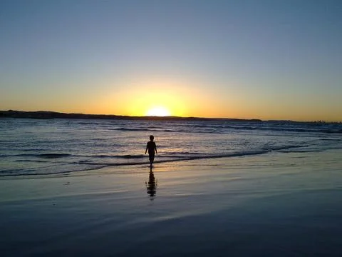 Boy at water's edge at dusk Stock Photos