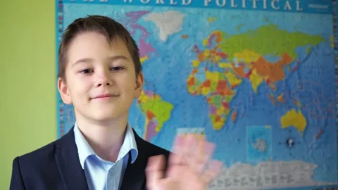 The boy waves his hand standing against the background of the world map. a smile Stock Footage 167559491