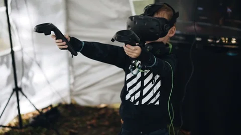 The boy waves his hands with a virtual reality helmet on his head. Cool footage Stock Footage 114536211