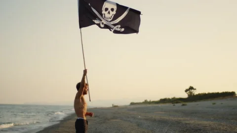 Boy waving pirate flag on a desert island Stock Footage 212687442
