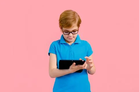 Boy wearing glasses using a tablet on a pink background Stock Photos