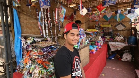 Boy wearing hat backwards in front of a kite shop in India Stock Footage 84625333
